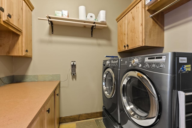 washroom featuring cabinet space, washer and dryer, and baseboards