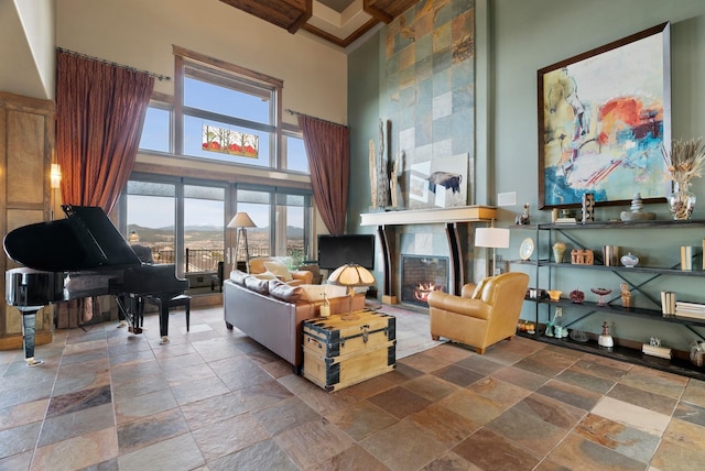 living room featuring a high ceiling, stone tile flooring, and a tile fireplace