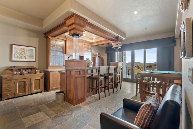 kitchen featuring ornate columns, a breakfast bar, stone tile flooring, a textured ceiling, and a center island