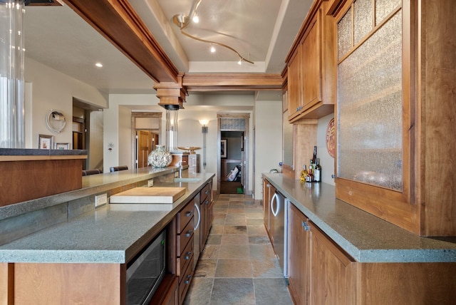 kitchen with stone finish flooring, brown cabinetry, and a sink