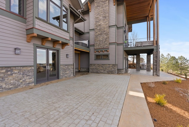 exterior space with french doors, stone siding, and a patio