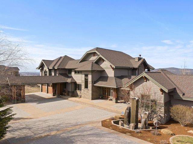 view of front of home with stone siding, driveway, and a chimney