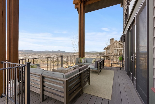 wooden terrace featuring a mountain view and an outdoor living space with a fire pit