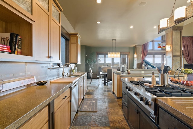 kitchen featuring glass insert cabinets, decorative light fixtures, stone tile floors, appliances with stainless steel finishes, and a sink