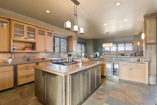 kitchen with backsplash, a kitchen island, glass insert cabinets, wine cooler, and light countertops