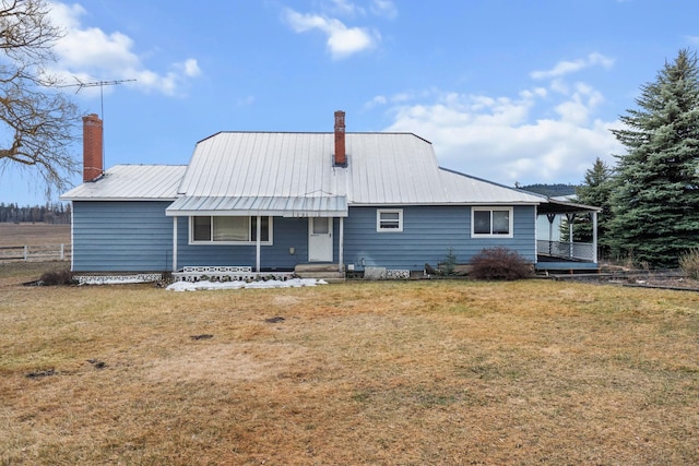 back of property with a chimney, a yard, and metal roof