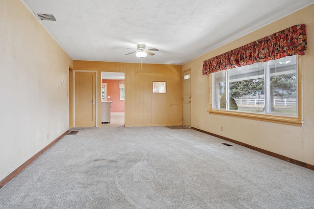 carpeted spare room with a healthy amount of sunlight, visible vents, and ceiling fan