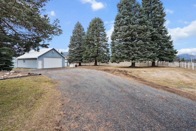 exterior space featuring a garage, driveway, an outdoor structure, and fence