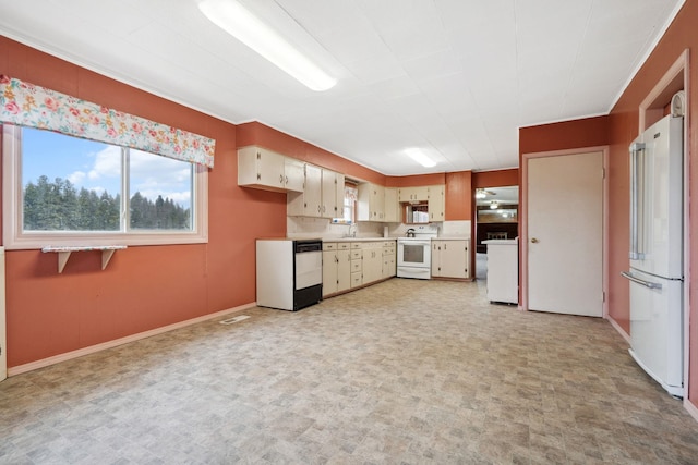 kitchen featuring light floors, light countertops, cream cabinetry, white appliances, and a sink