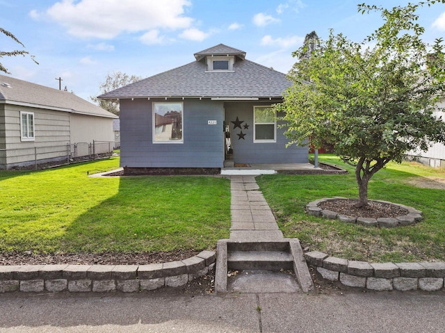 bungalow-style home featuring a front lawn, fence, and roof with shingles