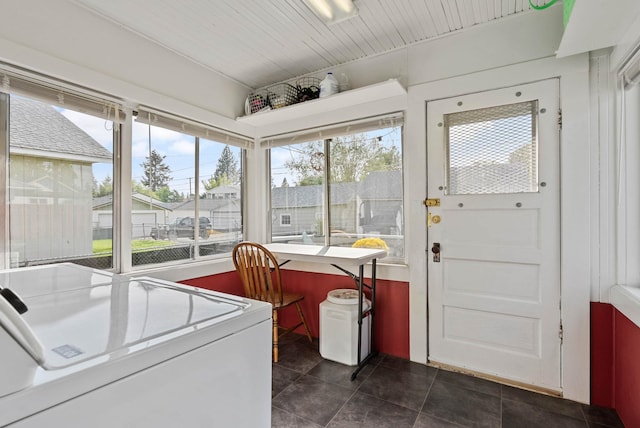 washroom featuring dark tile patterned floors, laundry area, plenty of natural light, and washing machine and clothes dryer