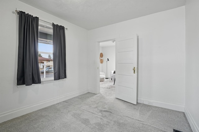 unfurnished room with baseboards, a textured ceiling, and carpet flooring