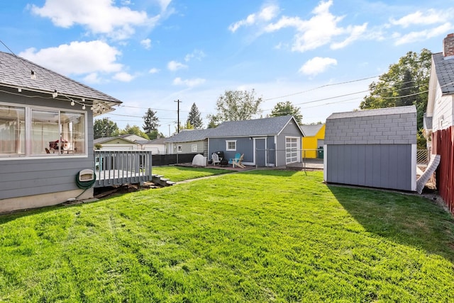 view of yard featuring a storage shed, an outbuilding, a fenced backyard, and a wooden deck