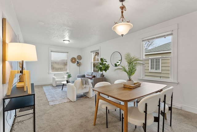 dining area featuring a wealth of natural light, baseboards, and light colored carpet