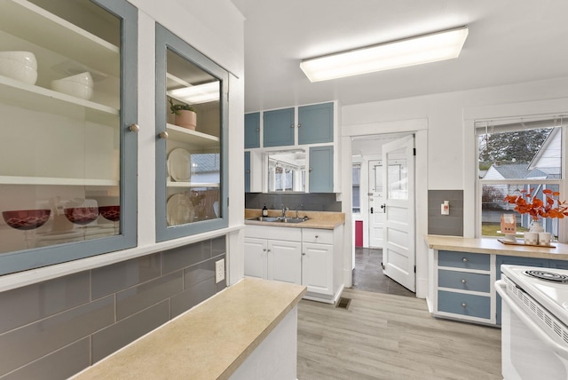 kitchen featuring light wood-style flooring, a sink, tasteful backsplash, white electric range oven, and light countertops