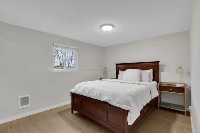 bedroom featuring visible vents, baseboards, and wood finished floors