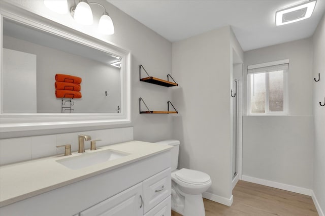 bathroom with vanity, wood finished floors, baseboards, a shower stall, and toilet