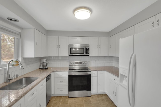 kitchen with backsplash, white cabinetry, stainless steel appliances, and a sink