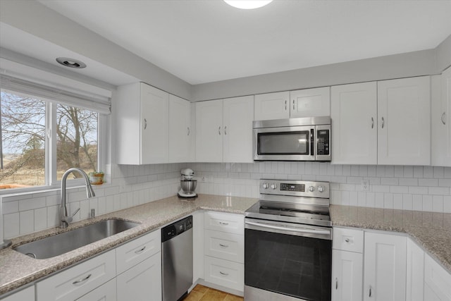 kitchen featuring a sink, white cabinets, backsplash, and stainless steel appliances