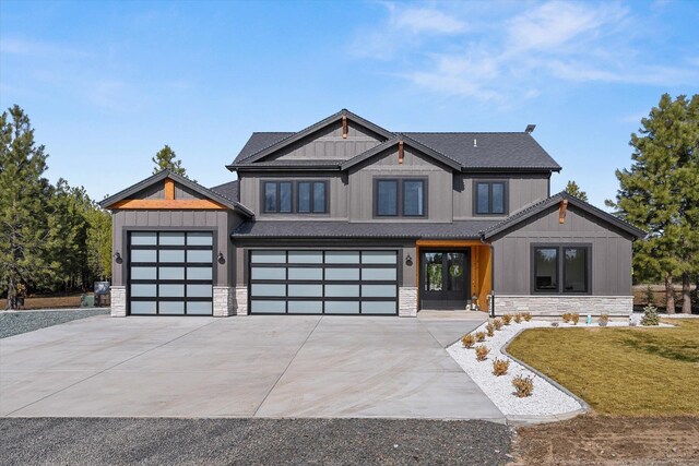 view of front of house featuring stone siding, driveway, a front yard, and board and batten siding