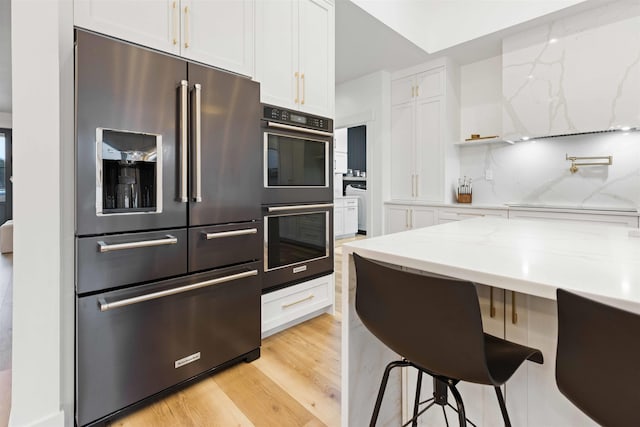 kitchen with decorative backsplash, double wall oven, high quality fridge, and white cabinetry