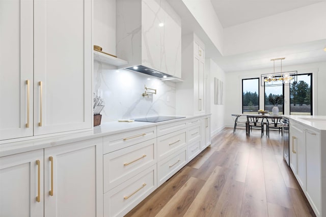 kitchen with tasteful backsplash, black electric stovetop, light wood-style floors, white cabinetry, and wall chimney exhaust hood