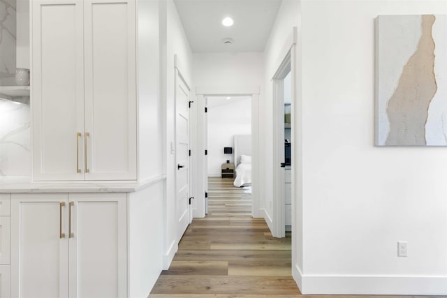 hall featuring recessed lighting, baseboards, and light wood-style flooring