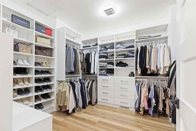 walk in closet with visible vents, attic access, and wood finished floors