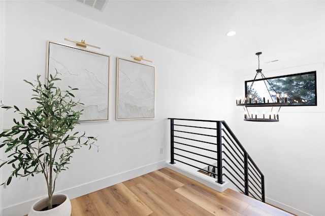 stairway featuring wood finished floors, visible vents, baseboards, recessed lighting, and a notable chandelier