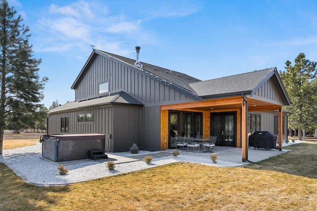 rear view of property featuring a patio, a yard, a shingled roof, a hot tub, and board and batten siding