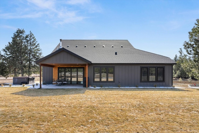 rear view of house featuring a patio area, board and batten siding, a hot tub, and a yard