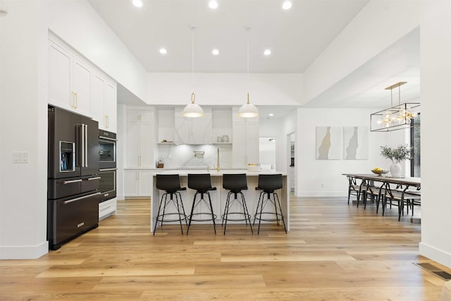 kitchen featuring tasteful backsplash, white cabinets, light countertops, and high end black fridge