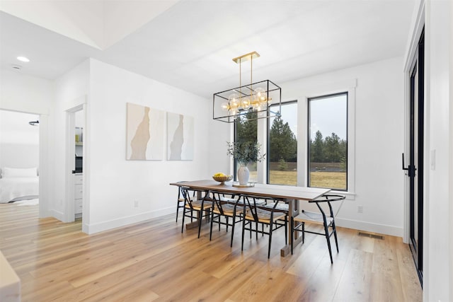 dining area with an inviting chandelier, light wood-style flooring, baseboards, and visible vents