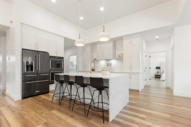 kitchen with tasteful backsplash, high end fridge, white cabinetry, and light countertops