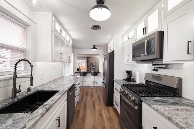 kitchen with a healthy amount of sunlight, white cabinetry, stainless steel appliances, and a sink