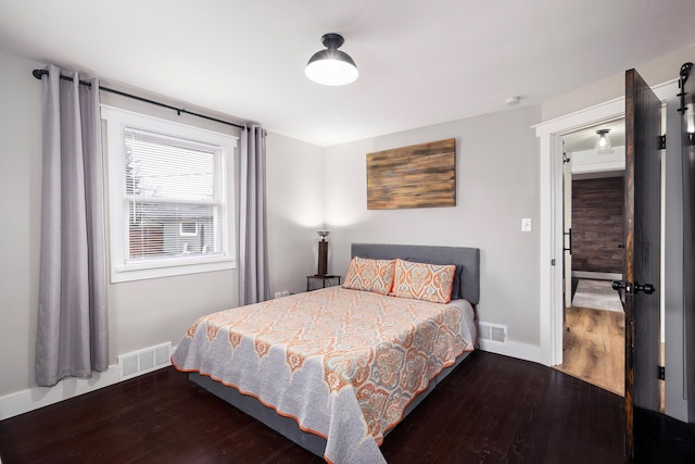 bedroom with visible vents, baseboards, and wood finished floors