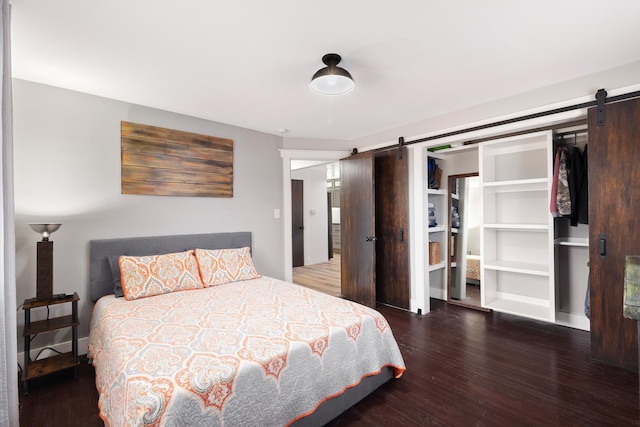 bedroom featuring a barn door, wood finished floors, and baseboards