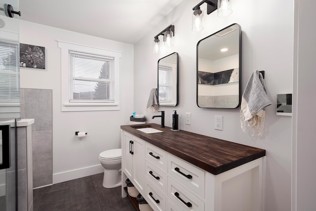 full bath with vanity, baseboards, tile patterned flooring, walk in shower, and toilet