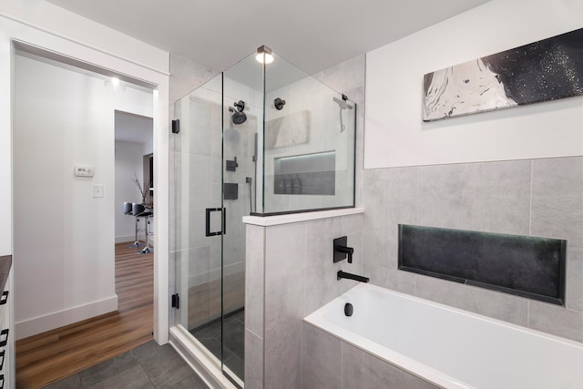 bathroom with a shower stall, a bath, baseboards, and tile patterned floors