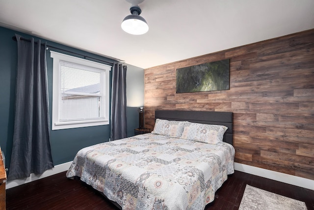 bedroom with wooden walls, baseboards, and wood finished floors