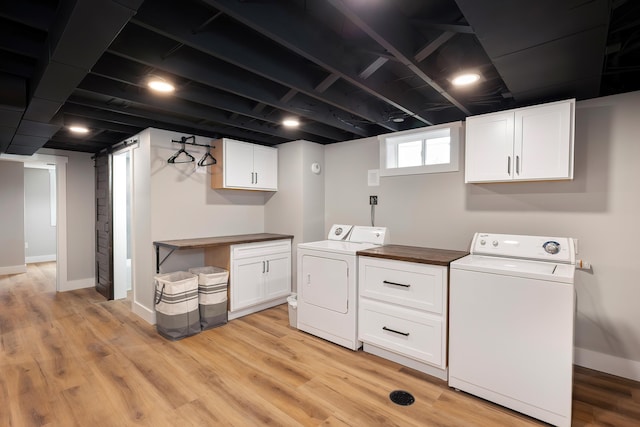 laundry room featuring washing machine and dryer, cabinet space, baseboards, and light wood-style floors