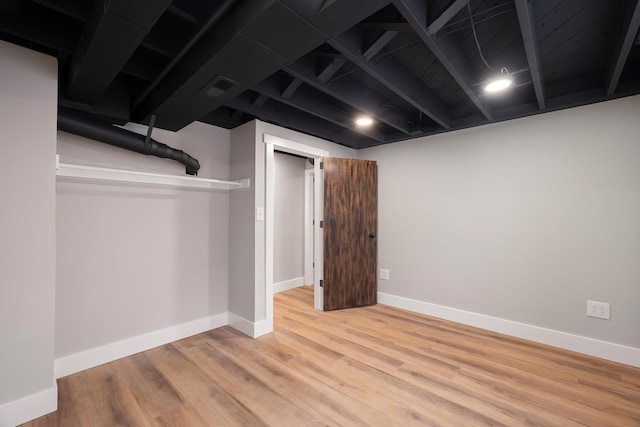 finished basement with visible vents, baseboards, and wood finished floors