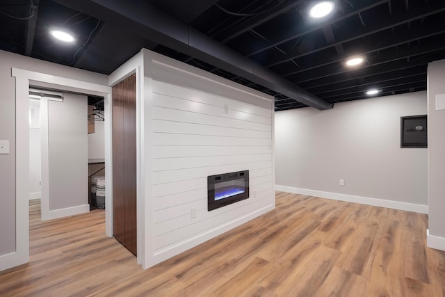 finished below grade area featuring recessed lighting, a fireplace, baseboards, and light wood finished floors