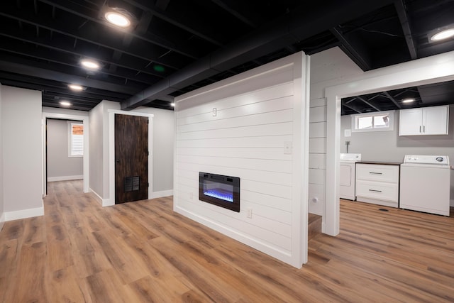 basement with independent washer and dryer, wood walls, a fireplace, light wood finished floors, and baseboards