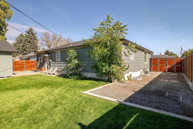 back of property featuring a gate, a patio area, a lawn, and fence