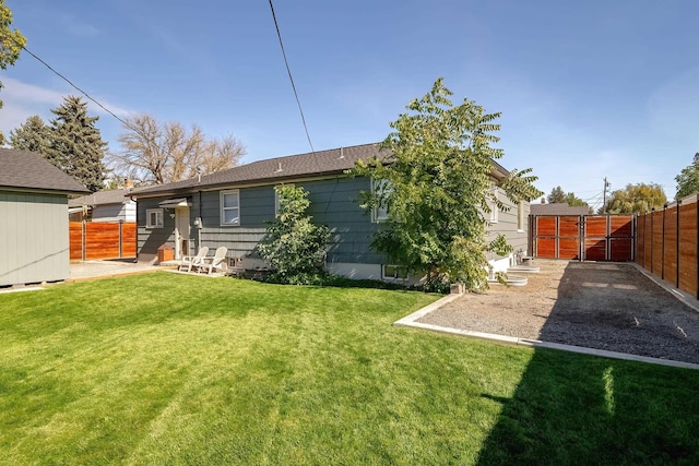 back of house with a gate, a lawn, and fence