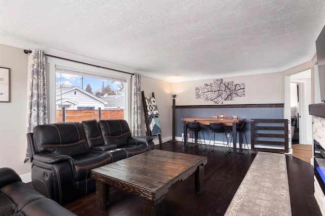 living room with baseboards, a textured ceiling, and wood finished floors