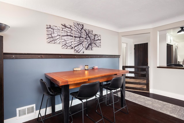 dining room featuring visible vents, baseboards, and wood finished floors