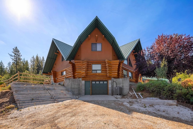 view of front of home with dirt driveway, log siding, metal roof, an attached garage, and a standing seam roof