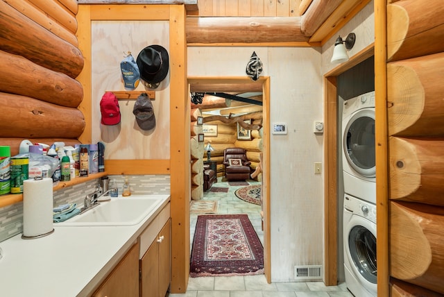 laundry area with a sink, visible vents, laundry area, and stacked washing maching and dryer